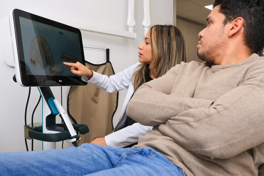 Dentist pointing at a 3D scan of a patient's teeth on the chairside screen