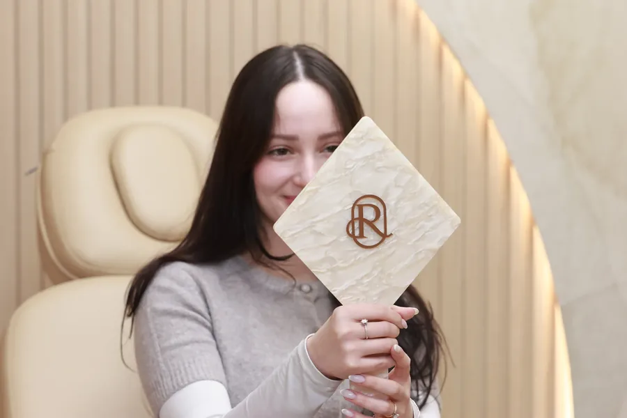 Smiling patient in the dental spa room holding the Restore Dental monogram sign