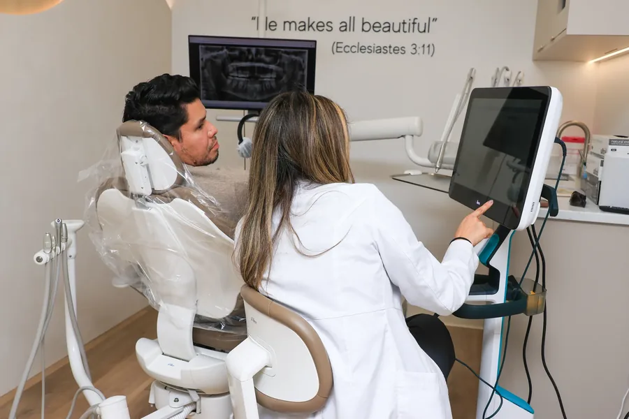 Dentist and patient reviewing a panoramic X-ray on the treatment room screen