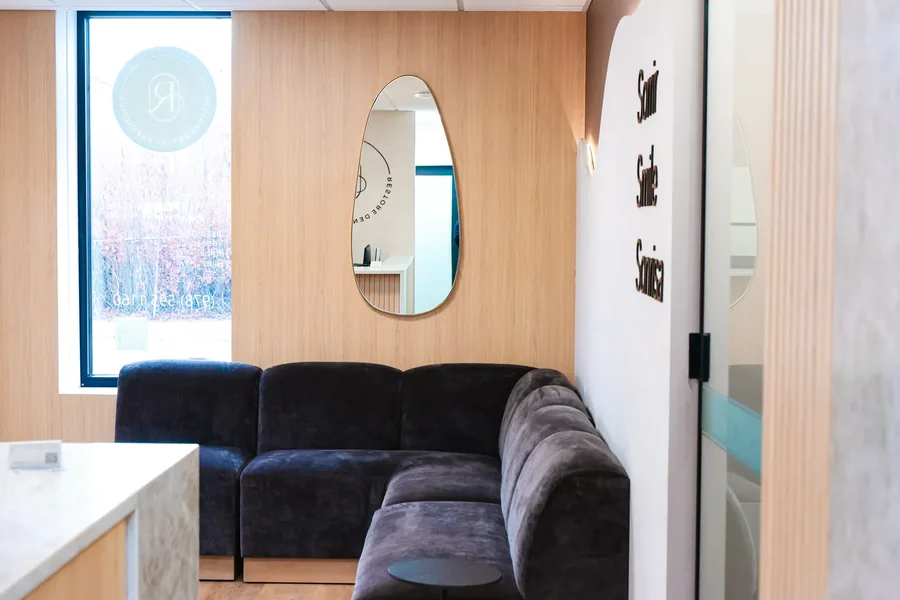 Waiting room with the Restore Dental logo on the window and a mirror on the wood panel wall